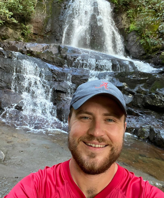 Evan Newman standing in front of waterfall