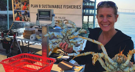 Woman holding two crabs up at a market